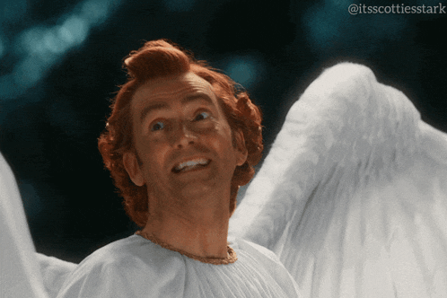 a man with red hair and white wings is smiling in a photo taken by itsscottiesstark