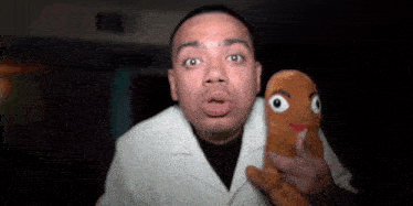a man in a white coat is holding a stuffed animal in his hands .