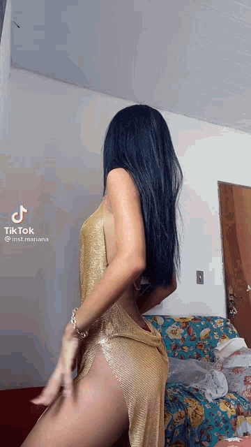 a woman in a gold dress is dancing on a couch in a living room .