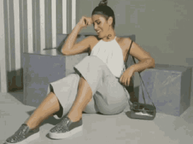 a woman is sitting on the ground with her legs crossed and a bag .