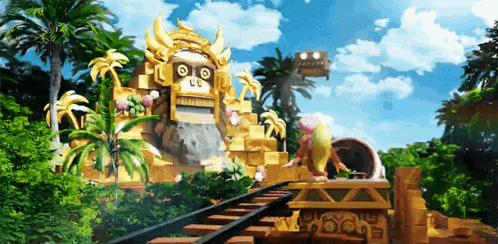 a roller coaster going through a jungle with a statue in the background that says ' lg ' on it