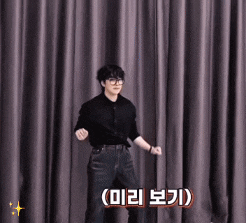 a man wearing glasses is dancing in front of a curtain .