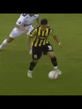 a soccer player wearing a yellow and black striped jersey with the number 18 on it