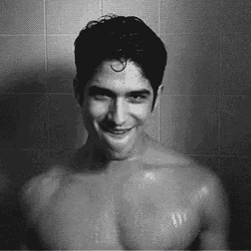 a shirtless man is taking a shower and smiling .