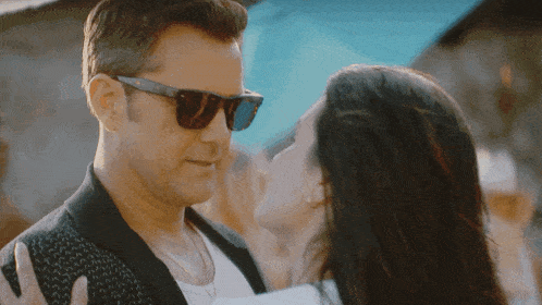 a man wearing sunglasses is kissing a woman on the forehead