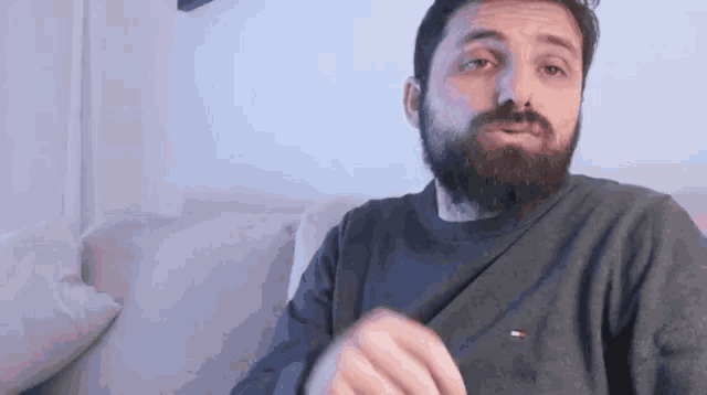 a man with a beard is wearing a tommy hilfiger sweatshirt