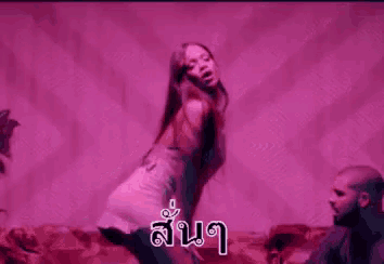 a man is kneeling down next to a woman who is dancing in a pink light .