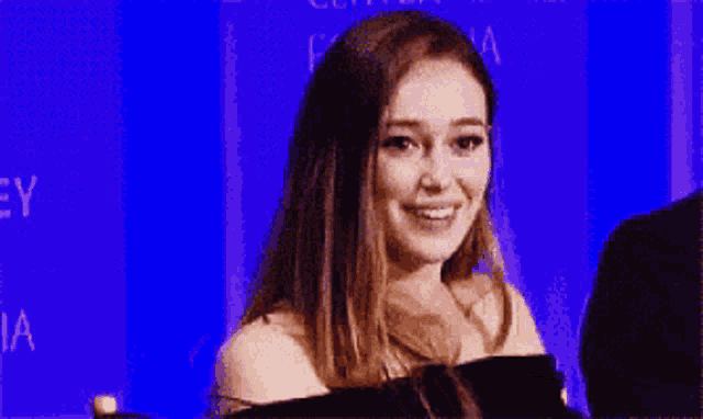 a woman in a black dress is standing in front of a blue wall with the word dia on it .
