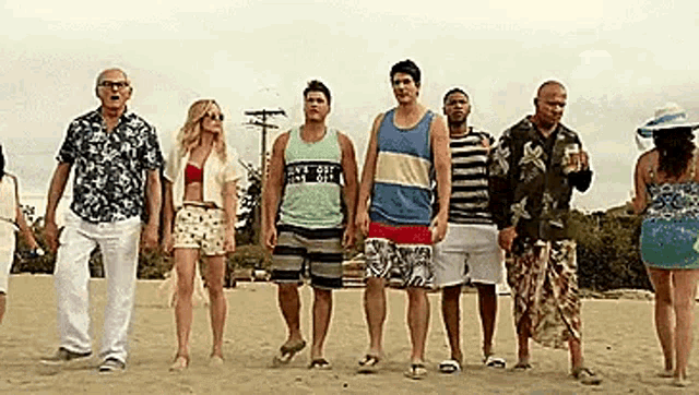 a group of people are standing on a beach holding hands .