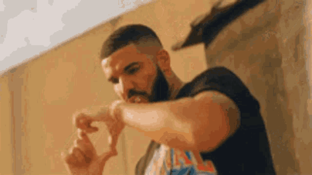 a man with a beard is making a heart shape with his hands while wearing a black shirt .