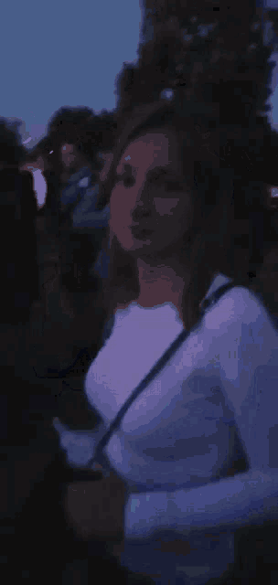 a woman in a white shirt is standing in a dark room