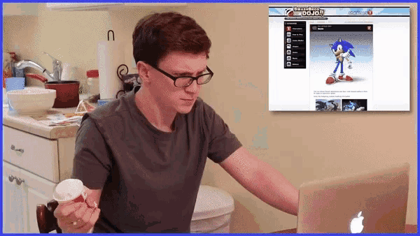 a man is eating ice cream while looking at a laptop screen that says sonic the hedgehog