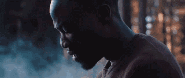 a close up of a man 's face in a dark room with smoke coming out of it .