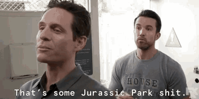 two men are standing next to each other and one of them is wearing a house shirt .