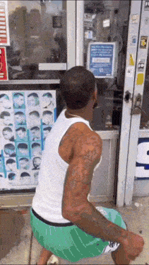 a man squatting in front of a store with a sign on the door that says ' covid-19 '