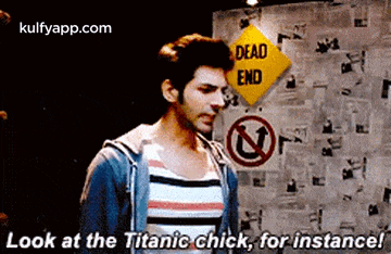 a man in a striped shirt is standing in front of a dead end sign .