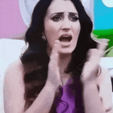 a woman in a purple shirt is making a funny face
