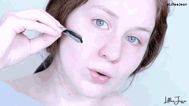 a woman is applying a cream to her face .