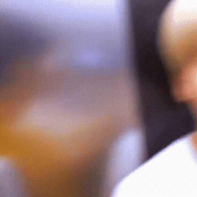 a blurry picture of a man 's face with a glass of orange juice in the background .