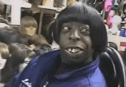 a man with a wig on his head is sitting in a chair in front of a mannequin .