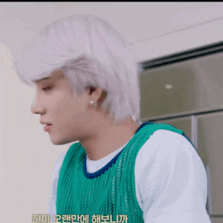 a young man with white hair is wearing a green vest