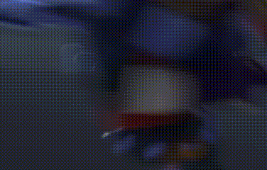 a pixelated image of a cartoon character with a red hat and yellow eyes standing in a dark room .