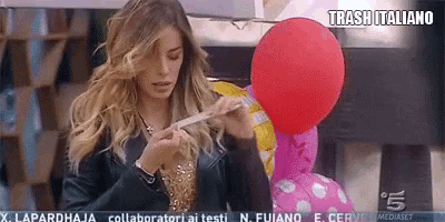 a woman in a black jacket is holding a red balloon in front of a sign that says trash italiano