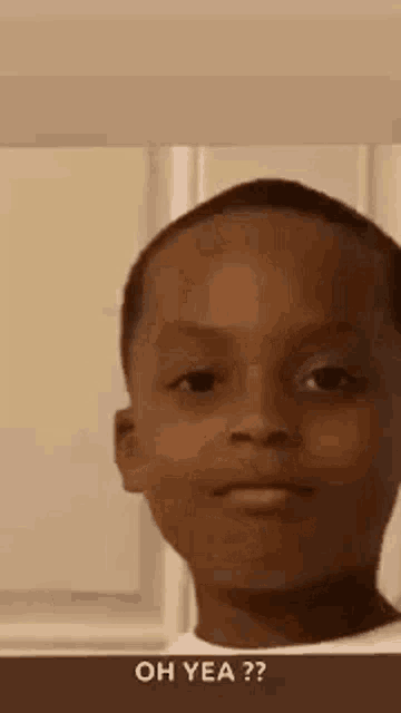 a young boy is making a funny face while standing in front of a window .