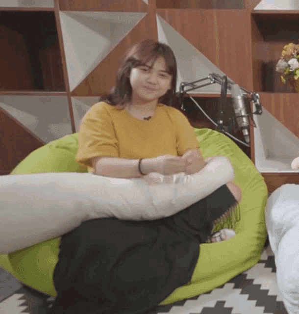 a girl in a yellow shirt is sitting on a bean bag chair