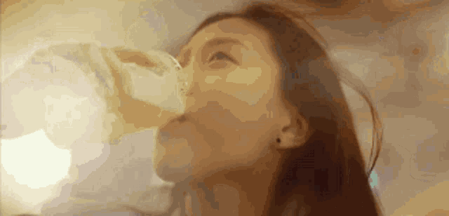 a woman is drinking a glass of water from a plastic bottle .