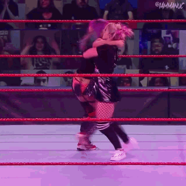 two women are hugging each other in a wrestling ring with the words i am manucu on the bottom