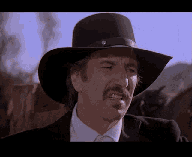 a man with a mustache wearing a cowboy hat and a suit