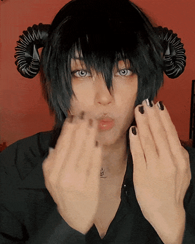 a person with horns on their head is making a heart with their hands