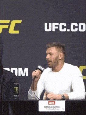 a man speaking into a microphone in front of a sign that says ufc on it
