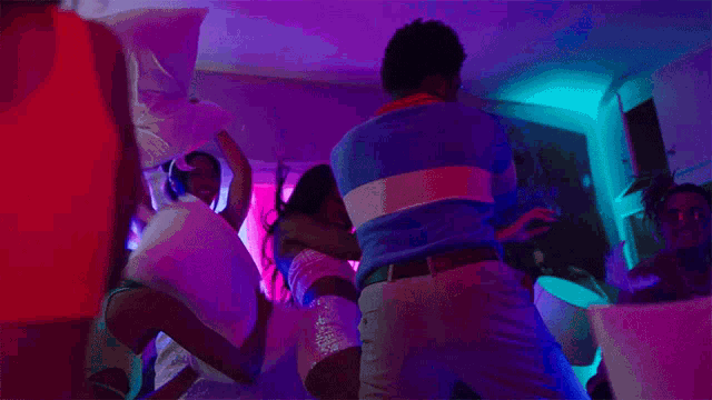 a group of people dancing in a room with purple and pink lights