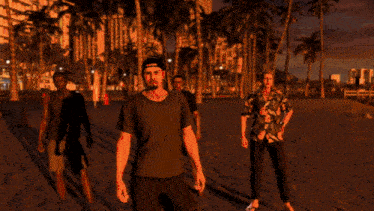 a group of people are standing on a beach and one of them has a t-shirt that says vans