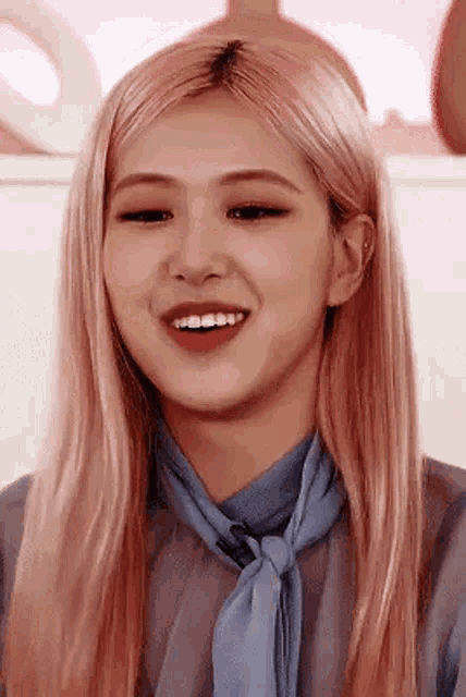 a close up of a woman with pink hair wearing a blue scarf and a blue shirt .