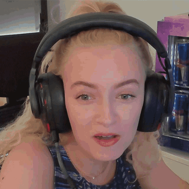 a woman wearing headphones looks at the camera with a red bull can in the background
