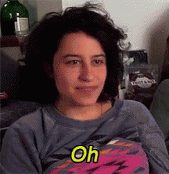a woman is sitting on a couch wearing a blue shirt and a pink shirt with the word oh on it .