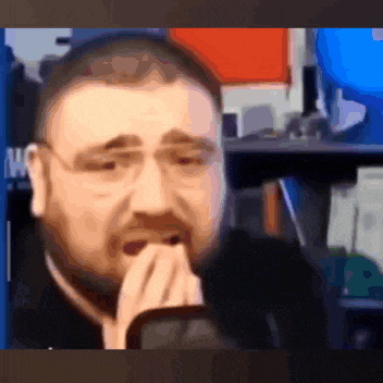 a man with glasses and a beard is covering his mouth with his hands