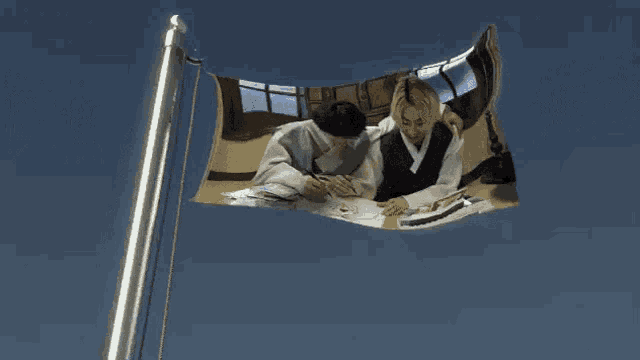 a picture of two people sitting at a table with a blue sky behind them