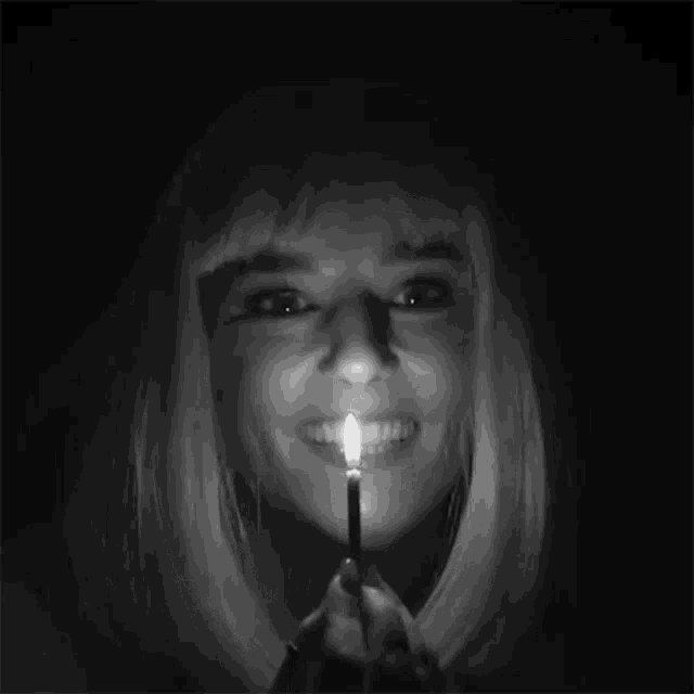 a woman with blonde hair is holding a lit match in her mouth ..