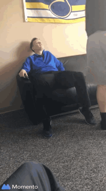 a man sits on a couch in front of a banner that says tm on it