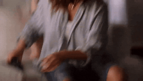 a woman in a robe is sitting on a couch and dancing .