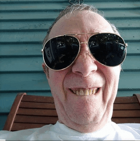 a man wearing sunglasses and a white shirt is smiling for the camera