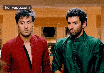 two men are standing next to each other in a living room .