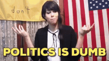 a woman is standing in front of an american flag and saying politics is dumb .