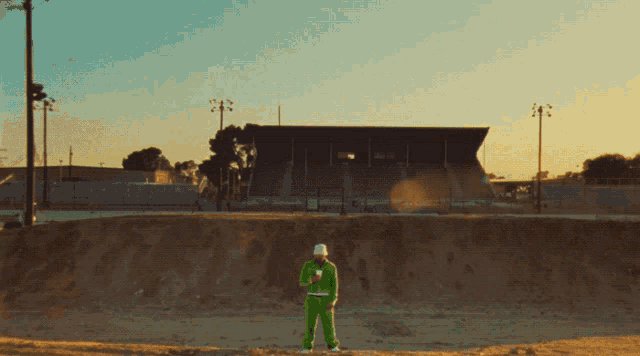 a man in a green track suit stands in front of a stadium