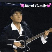 a man is singing into a microphone while holding a guitar in front of a royal family logo