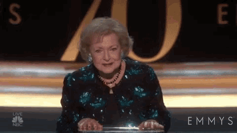 a woman is sitting at a podium giving a speech at an emmy awards show .